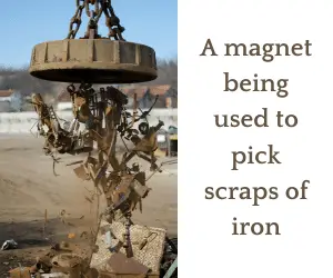 A magnet being used to pick scraps of iron
